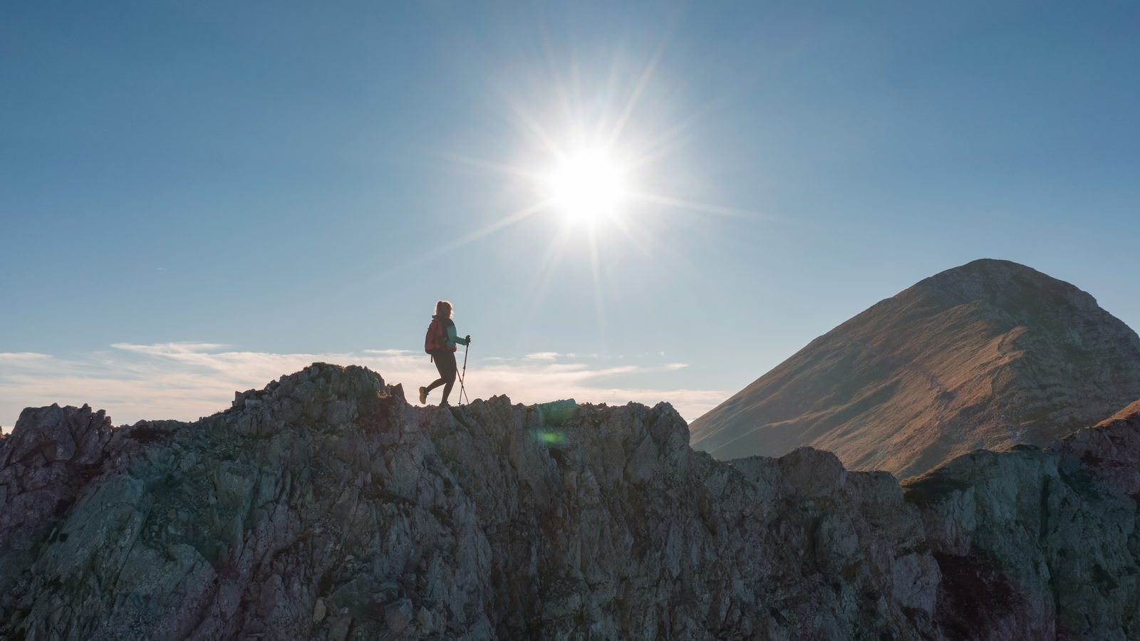 Einzelne Wanderin als Silhouette auf einem Grat bei Sonnenuntergang