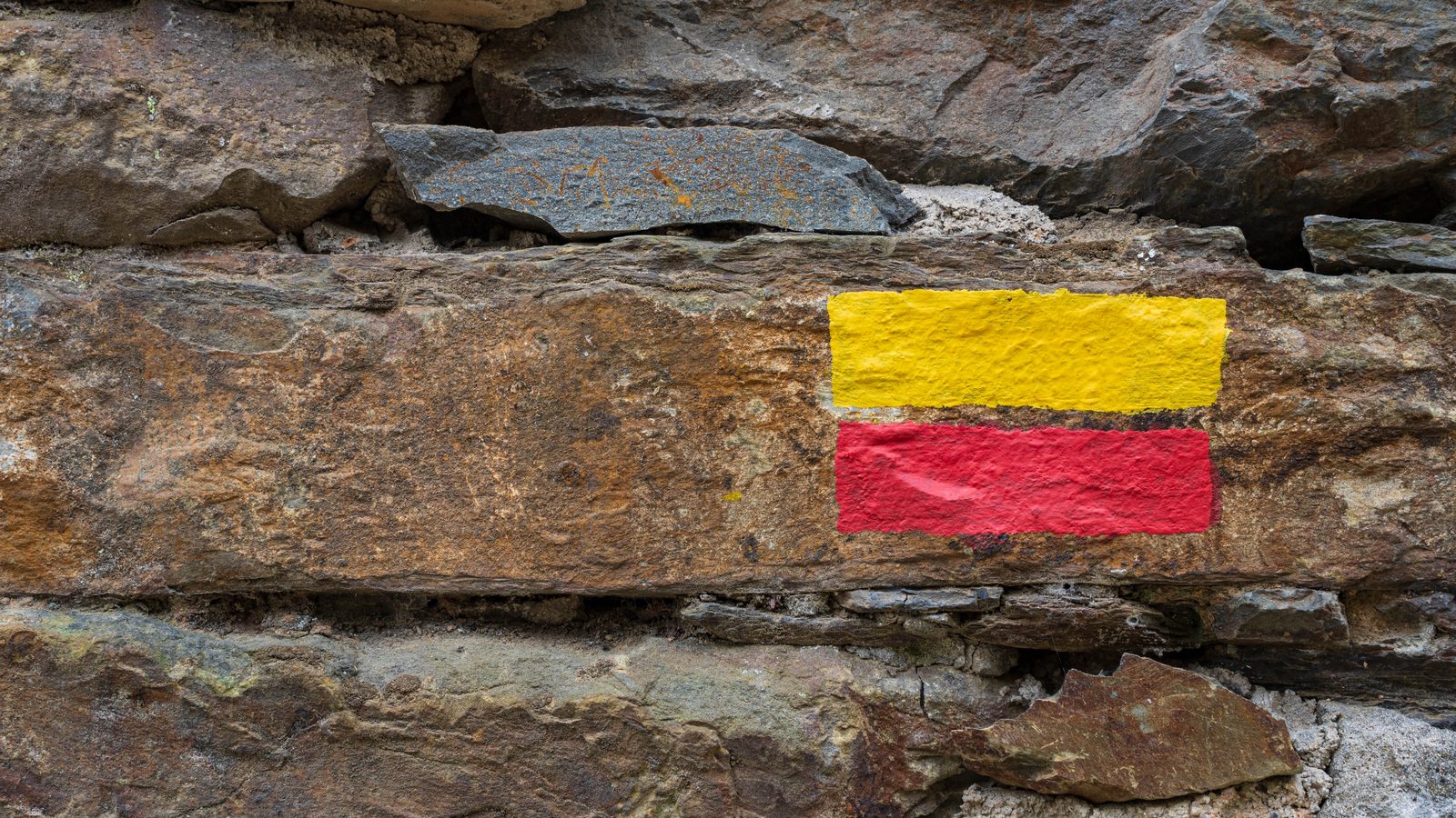 A red-and-yellow painted waymark on a dry-stone wall — the colour used on some alternative routes; the main Lycian Way is marked red over white